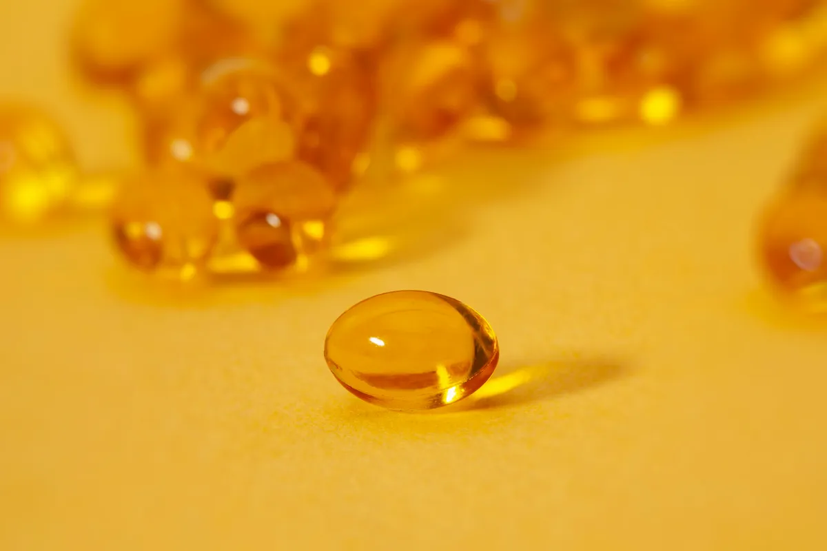 Cápsulas de aceite de omega 3 sobre una superficie amarilla